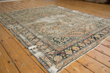 Distressed vintage Dargezine carpet with worn dusty rose field, navy border, and floral motifs.