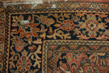 Corner of a vintage Mahal carpet showcasing intricate brick red floral arabesque and blossom motifs on navy.