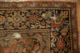 Corner of a vintage Mahal rug with navy field, brick red border, floral motifs, and visible foundation.