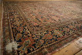 Worn corner of the circa 1930s Mahal carpet, showing navy floral border and exposed foundation.