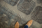 Distressed vintage Ersari carpet displaying geometric gul patterns in beige, charcoal, and soft silver tones.