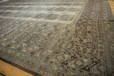 Distressed vintage Ersari carpet with geometric border motifs and muted beige, charcoal pile.