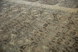 Distressed Ersari carpet detail showing geometric guls in beige, charcoal, and soft silver.