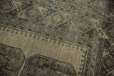 Distressed Ersari rug detail showing geometric elephant's footprint gul motifs in beige and charcoal.