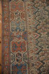Antique Malayer runner's terracotta, blue geometric border, visible knot heads, and checkered field.