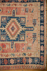 Corner detail of distressed vintage Karaja runner with navy geometric border, blush field, and even pile wear.