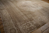 Abrashed vintage Oushak rug detail: subtle sand field, pomegranate border, distressed texture.