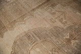 Distressed Oushak carpet close-up with abrashed field, showing stepped medallion outline in sand and blush.