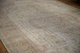 Distressed texture of vintage Sivas carpet showing faded ivory and dusty rose floral motifs.