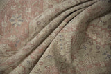 Folded Sivas rug showcasing distressed texture, faded dusty rose and ivory floral patterns.
