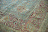 Detailed corner of a distressed Meshed carpet, showing faded powder blue, blush, and gold floral vinery.