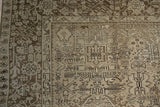 Textured corner of the distressed Karaja carpet, showcasing geometric palmette gul motifs in silver and chocolate charcoal.