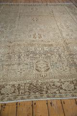 Distressed vintage Karaja rug's ivory and chocolate geometric palmette pattern detail.