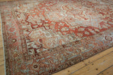 Corner of distressed vintage Heriz rug with red, ivory, and blue geometric spandrels.