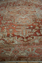 Distressed vintage Heriz rug pile showing geometric and floral motifs in chestnut, blue, and ivory.