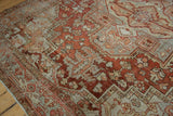 Distressed Heriz carpet's worn pile, chestnut red and dusty blue geometric patterns with intact selvage.