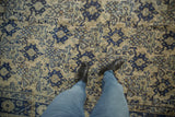 Close-up of distressed Oushak rug, cobalt blue floral motifs on faded ivory.