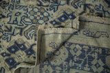 Vintage distressed Oushak carpet showing worn knot heads, blue floral motif, and folded selvage.
