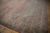 Distressed Kerman carpet corner showing intricate millefleur motifs in pale raspberry and dusty blue.