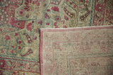 Distressed Kerman carpet showing worn floral pile, revealing hand-knotted foundation and fringe.