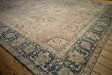 Distressed vintage Tabriz carpet's dusty blush field with palmettes and navy border.