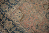 Distressed blush field of vintage Tabriz rug, revealing faded navy and beige floral motifs.