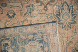 Distressed Tabriz carpet detail: faded floral design, aged blush, navy, and ivory hues, with hand-knotted selvage.