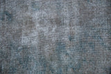Vintage Sparta carpet's distressed texture, revealing silver, oxidized grey, and dusty cobalt blue.