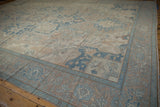 Distressed vintage Oushak rug border with pale blue and beige floral motifs.
