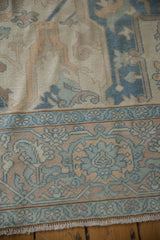 Vintage distressed Oushak rug corner with pale blue floral border and soft worn texture.