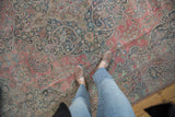 Distressed vintage Khorossan carpet with faded rose, blue, and teal curvilinear patterns.