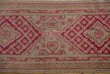 Distressed Khotan runner, raspberry red geometric lattice, diamond motifs, and worn pile.