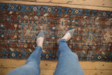Vintage Heriz runner's geometric pattern in chestnut, sky blue, and textured pile.