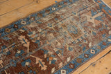 Vintage Heriz runner pile texture, showing chestnut brown checkered field and blue vine motifs.