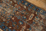 Heriz runner detail: chestnut brown, sky blue, rose checkered geometric motifs and visible knot heads.