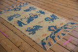 Close-up of antique Ningxia runner's pictorial Fu dog motifs, cobalt blue, apricot, on cream pile.