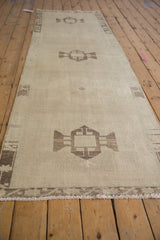 Distressed Oushak runner, highlighting its textured ivory pile, brown geometric medallion, and border.
