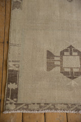 Distressed Oushak runner corner showing fringe, geometric border, and time-softened tones.