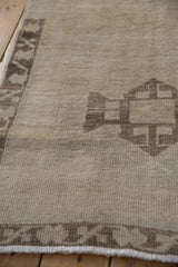 Distressed ivory pile texture of the Oushak runner, revealing a geometric border and softened tones.