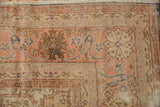 Distressed vintage Sparta rug corner, revealing faded apricot, beige, and blue scroll patterns.