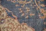 Distressed denim blue field of the hand knotted Sparta carpet, with apricot vinery and visible wear.