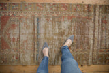 Close-up of distressed vintage Oushak runner, worn pile revealing foundation, with faded red and gold designs.