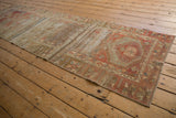 Distressed vintage Oushak runner showing faded madder root red, gold, and exposed foundation.