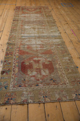 Textured close-up of vintage Oushak runner with distressed red and gold geometric floral motifs.
