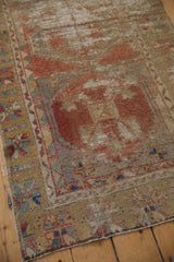 Distressed vintage Oushak runner corner, featuring faded madder red and golden geometric border detail.