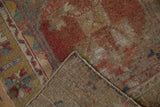 Folded corner of distressed Oushak rug, revealing worn madder red pile and hand-knotted reverse.