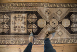 Distressed Oushak runner detail with geometric hook and latch motifs in beige and charcoal.