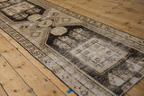 Distressed Oushak runner, highlighting geometric pinwheel and checkered patterns in ivory and black.