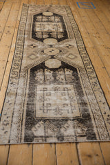 Distressed Oushak rug showing worn geometric hook and latch patterns in charcoal and ivory.