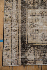 Distressed Oushak runner corner; ivory, charcoal, and black geometric motifs; low pile with visible foundation.
